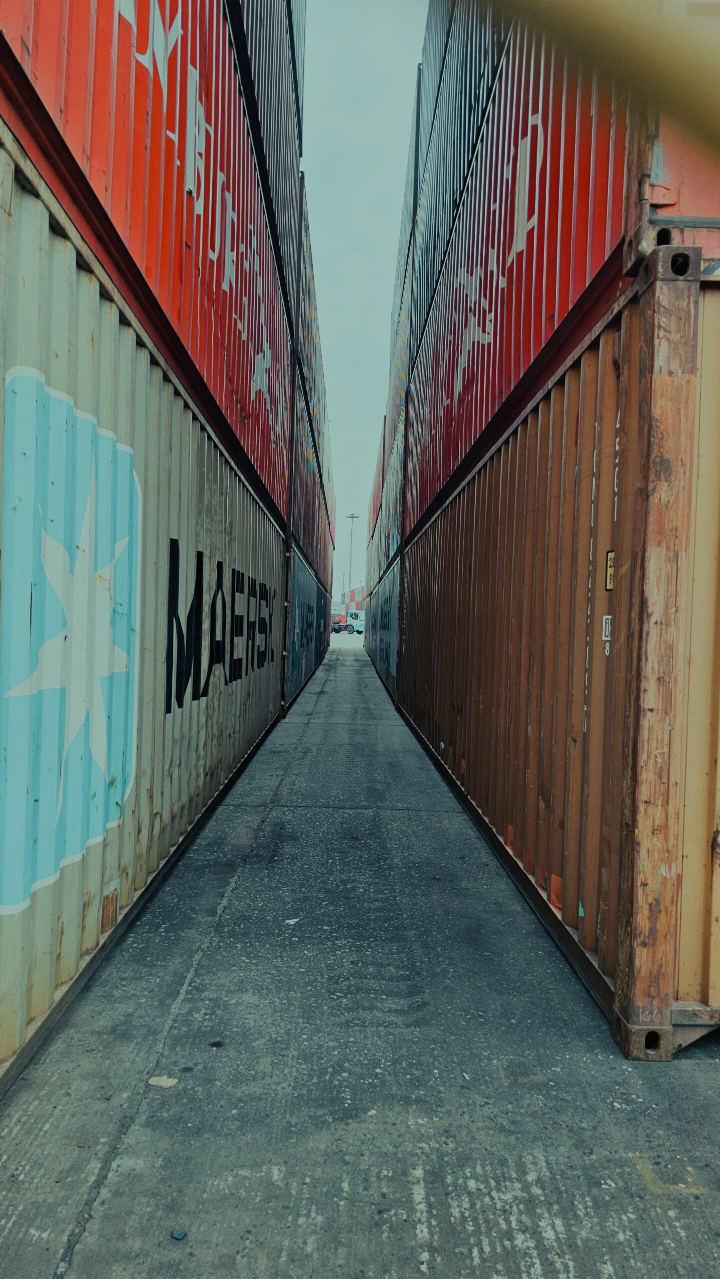 View down a narrow passage between colorful stacked shipping containers.